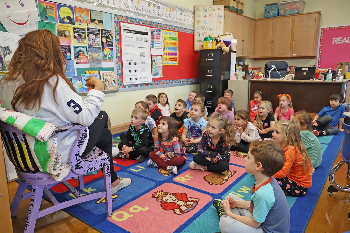 Students listening to a teacher read a book Students listening to a teacher read a book